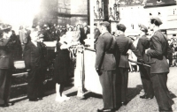 Slavnostní leteckou standartu drží zbrojíř 311. československé bombardovací perutě Viktor Kropš. (Jeho osud by rovněž vydal na knihu zejména svými dramaty po roce 1948. Jeho letka byla v roce 1946 převelena na letiště Plzeň-Bory. Při přehlídce uskutečněné právě v Plzni v roce 1945 se seznámil se svou budoucí chotí Jiřinou. Po únoru 1948 se spolu s ní za pomoci převaděče pokusili jedné noci projít domažlickými lesy za hranice, avšak byli zadrženi. Viktor i Jiřina se na pohraničníky vrhli, strhla se rvačka a Viktor chtěl použít i svůj revolver. Nicméně pohraničníci byli v přesile. Jiřina skončila na rok v ženské káznici a Viktor po dlouhém věznění s trýznivými výslechy nakonec v jáchymovských dolech, což mu natrvalo podlomilo zdraví. I této rodině se Jan v nejtěžších dobách snažil pomáhat a přátelské vazby se upevnily až do „rodinného“ pouta. Když Viktor po propuštění po několika málo letech na svobodě na následky věznění zemřel, byl Jan požádán, aby vyprovodil jejich dceru Šárku jako „druhý táta“ k oltáři, a naproti tomu Jiřinka „dělala druhou mámu“ Ivetě až do své smrti v roce 2014.)