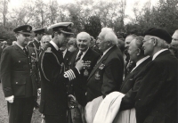 Další krásná momentka z pietní akce na Olšanech - za zády prince Charlese vykukuje část obličeje Jiřího Maňáka, Jan Irving se usmívá na jednoho ze svých nejlepších kamarádů, „drsňáka“ Bohumila Jaroše alias „Suchara“, po jehož levici s kabátem přes ruku stojí plk. Malý a vpravo v baretu plk. Petr Uruba. (I ten patřil spolu se Zdeňkem Škarvadou, Vildou Bufkou a dalšími mezi spoluzajatce ze Saganu a následně všichni po přesunu sdíleli společné kobky na slavném německém hradě pro zajaté vyšší důstojníky, Colditzu).