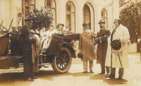Druhý zprava stojí Alfréd Schebek a blíže k nám v automobilu sedí jeho choť Helena